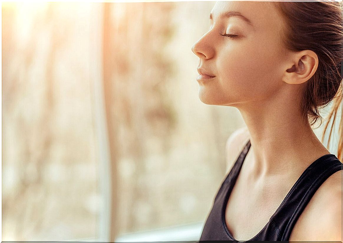 Woman with eyes closed near a window.