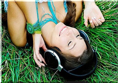 Woman lying on the grass listening to music.