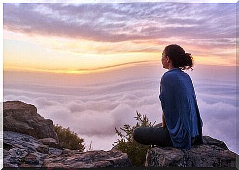 Woman meditating on top of mountain.