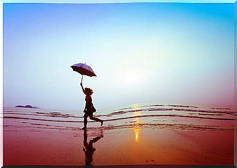 Woman walking on beach with umbrella.